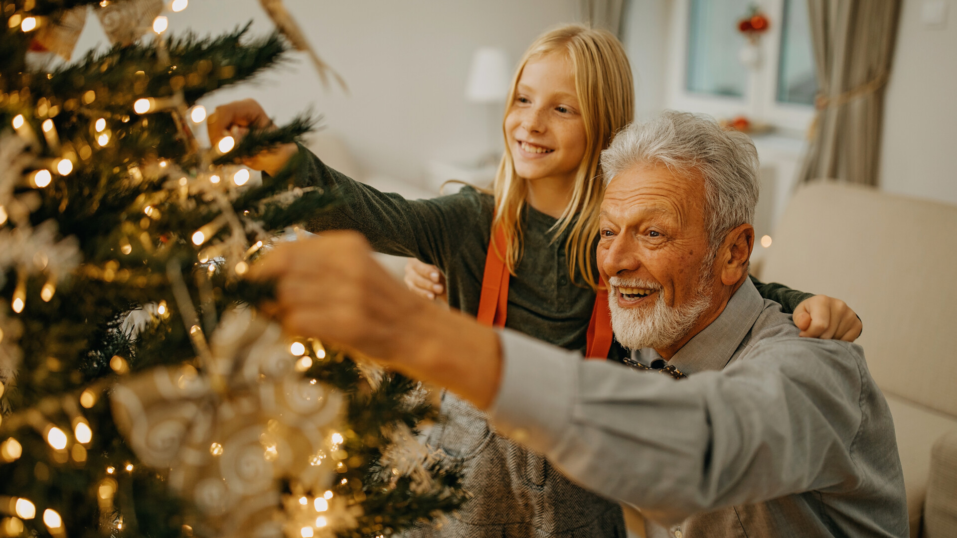 Senior Mann und Enkelin schmücken Weihnachtsbaum